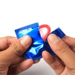 Man's Hands Unwrapping a Condom,Hand holding a condom